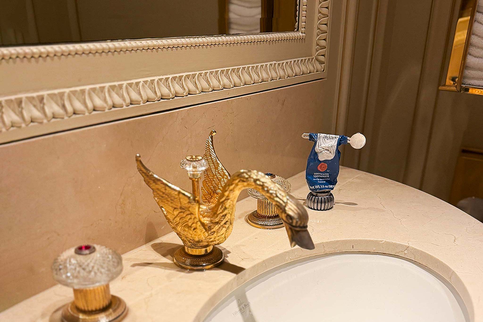 Akla toothpaste at sinkside with swan faucet in a luxrious setting.