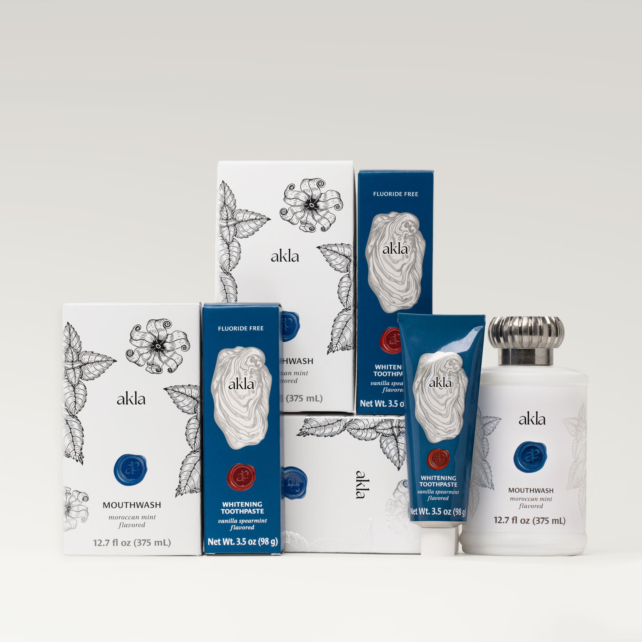 Akla oral care set including three Moroccan Mint Mouthwash bottles and two Vanilla Spearmint Whitening Toothpastes in full packaging display.