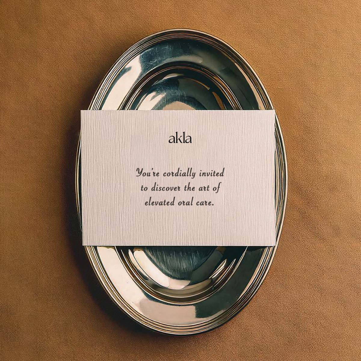 Akla invitation card on a silver tray, symbolizing luxury oral care and ceremonial elegance.