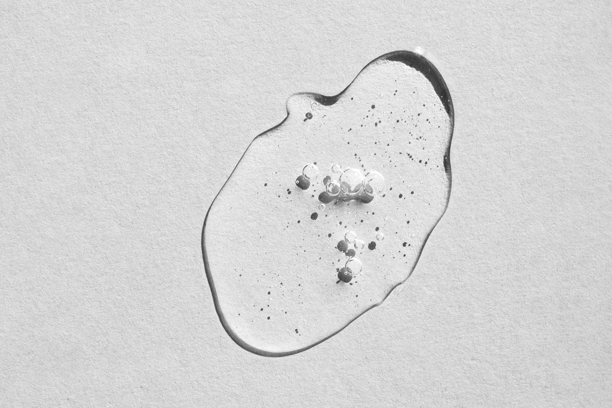 Closeup of a smear of glycerin on a light grey background representing the moisturizing glycerin in Akla oral care products.