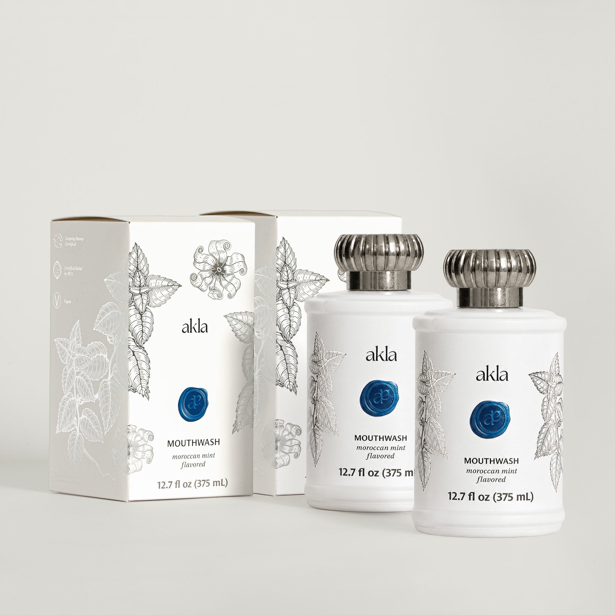 Akla Moroccan Mint Mouthwash with matching cartons. Alcohol-free botanical mouthwash in frosted white glass packaging, formulated in Switzerland.