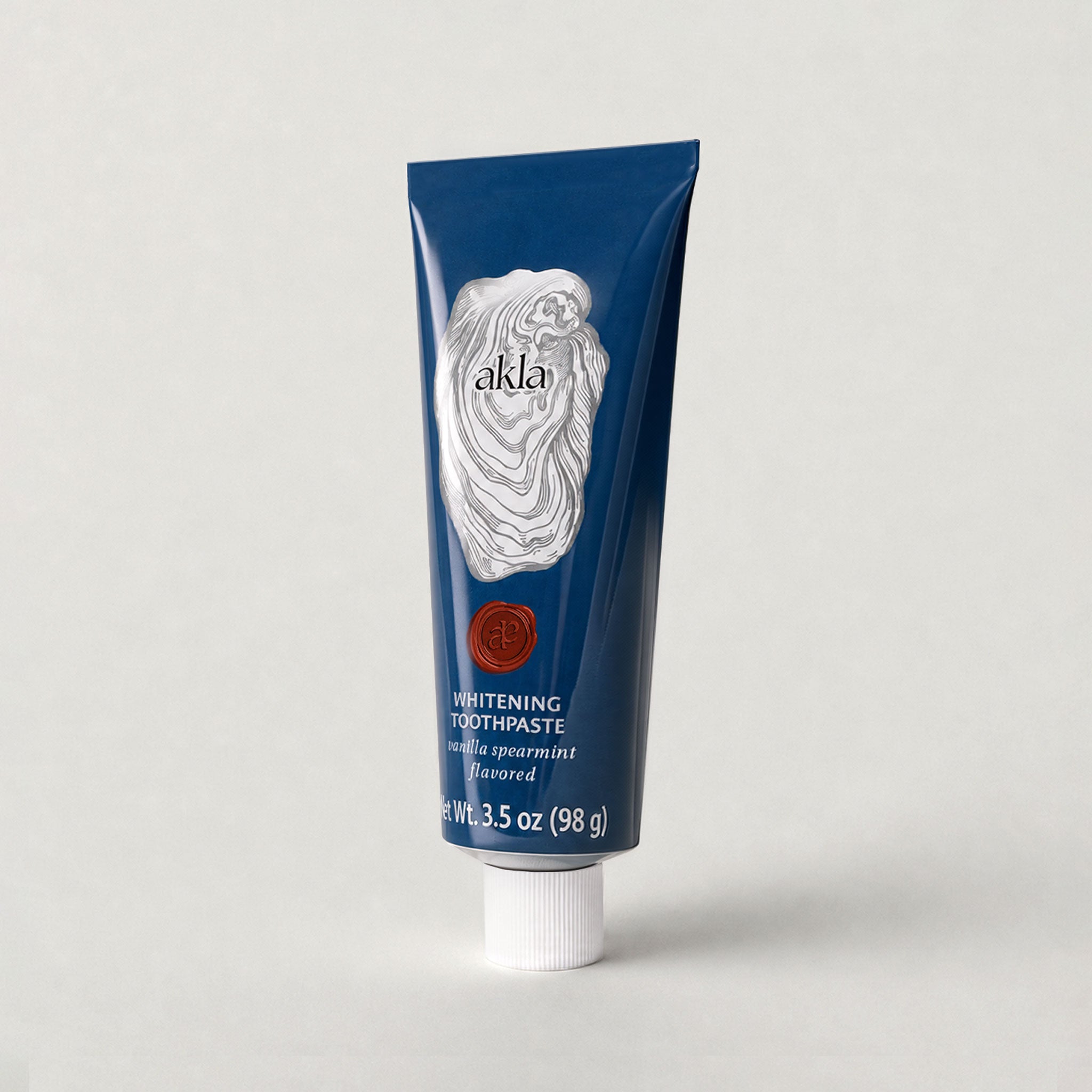 Akla Vanilla Spearmint Toothpaste shown at three-quarter angle in navy blue aluminum packaging. Swiss-made luxury oral care.