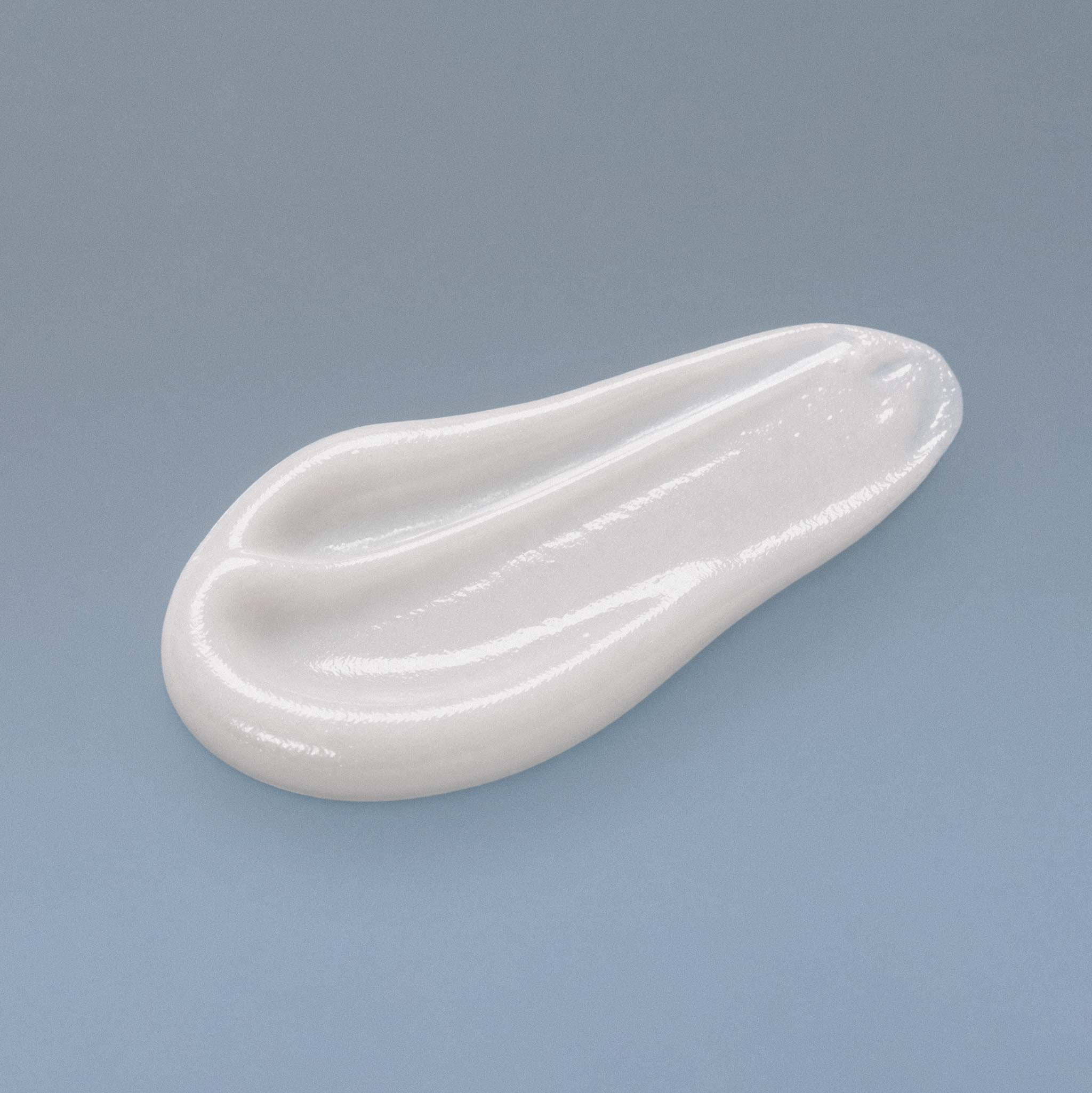 A smear of Akla's hydroxyapatite whitening toothpaste on a blue-gray background.