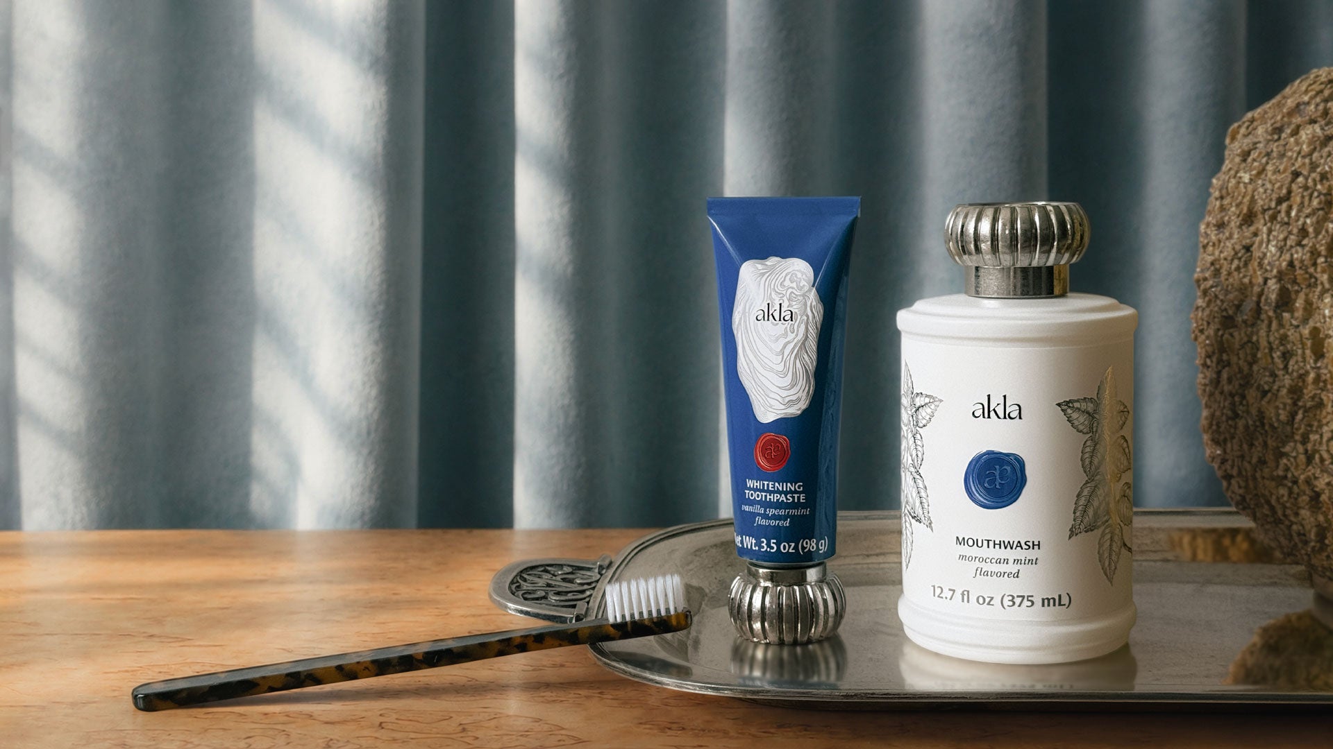 Akla hydroxyapatite toothpaste and alcohol-free mouthwash on a silver tray — Swiss-made fluoride-free luxury oral care