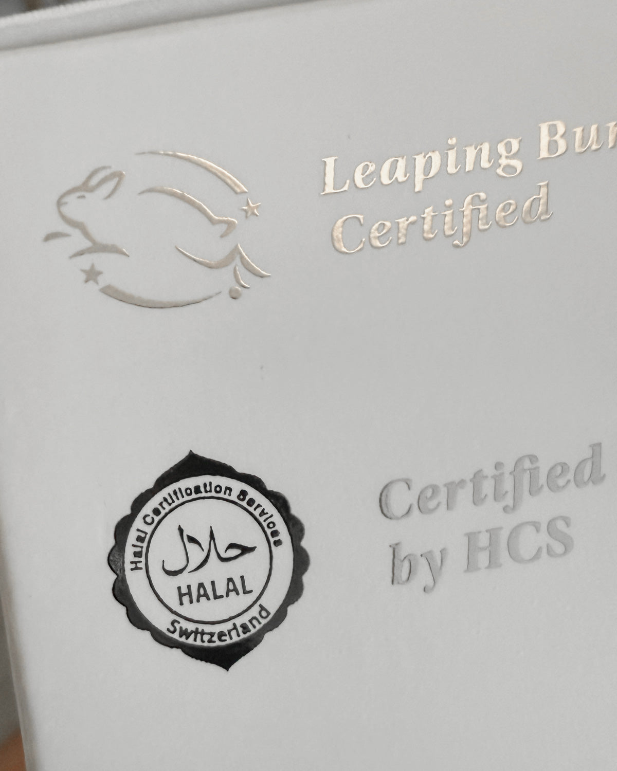 Product packaging with 'Leaping Bunny Certified' and 'Halal Switzerland' logos  in silver foil on a white background.