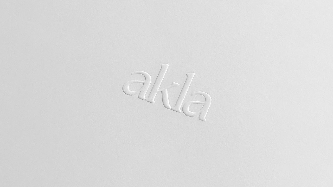 Embossed Akla logo on white paper background.