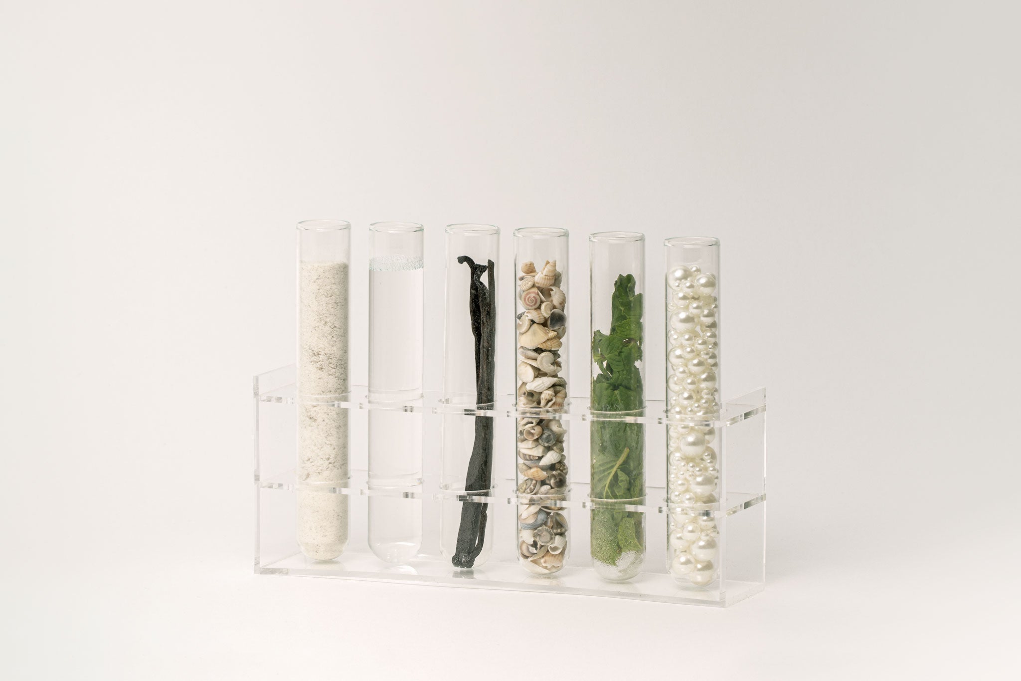 Oral care ingredients displayed in glass tubes, including mint leaves, pearls, and botanical extracts.