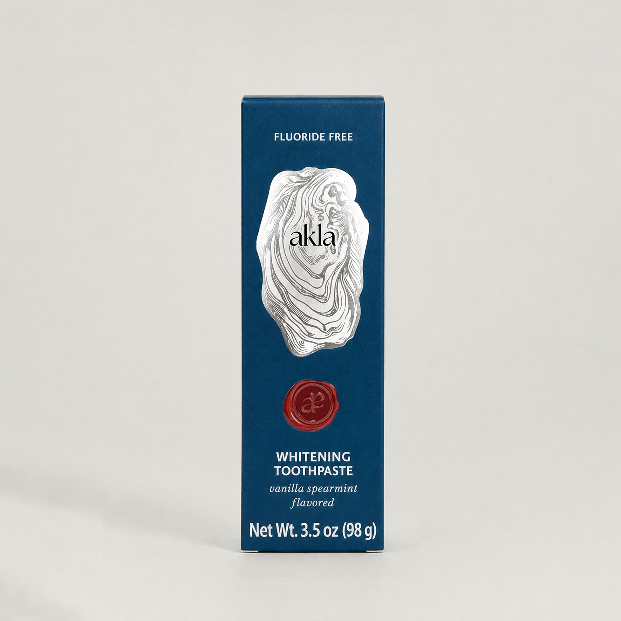 Akla fluoride-free toothpaste carton in heritage blue with silver oyster illustration. Swiss-made luxury oral care.