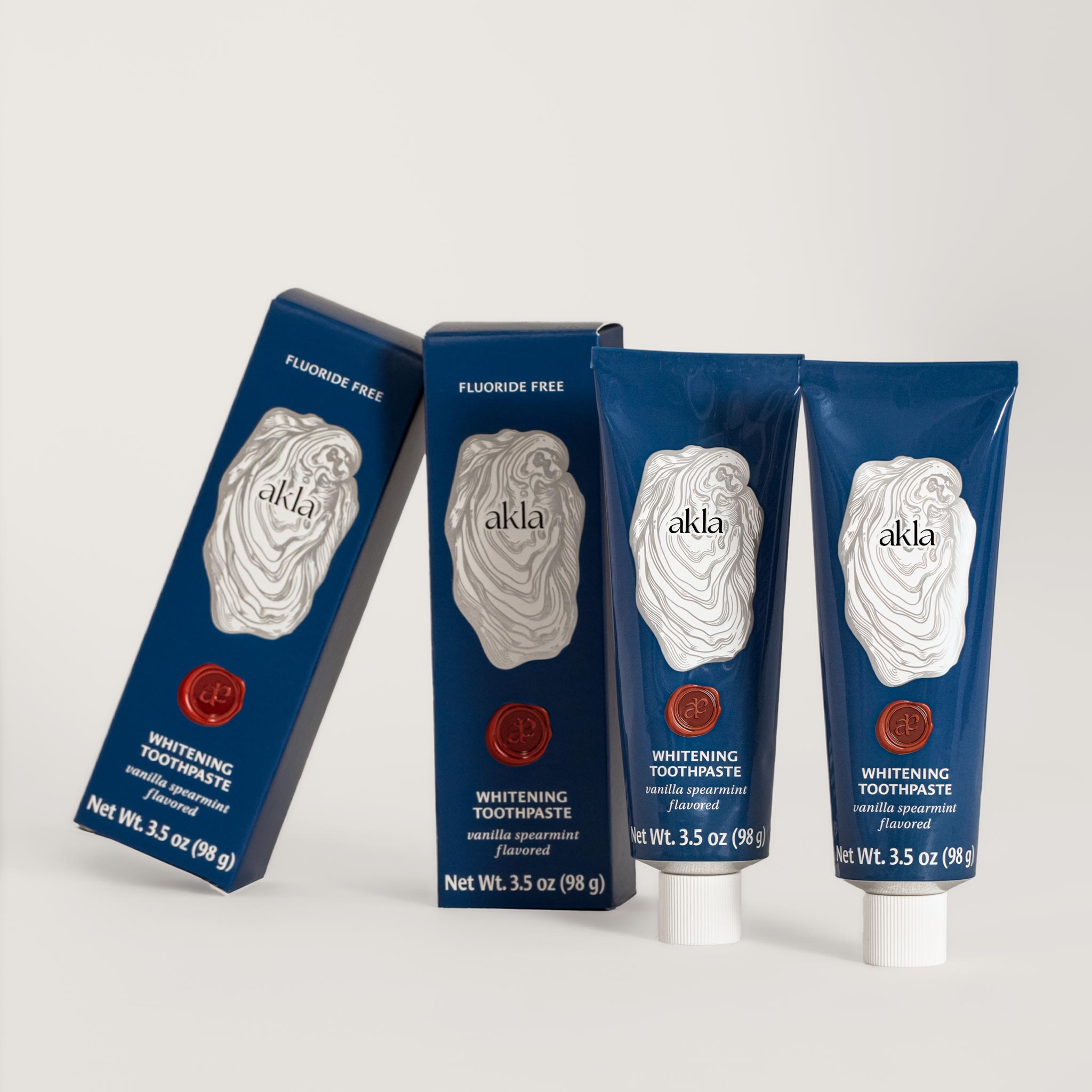 Akla Vanilla Spearmint Toothpaste with matching cartons. Fluoride-free non-nano hydroxyapatite toothpaste in blue aluminum packaging, formulated in Switzerland.