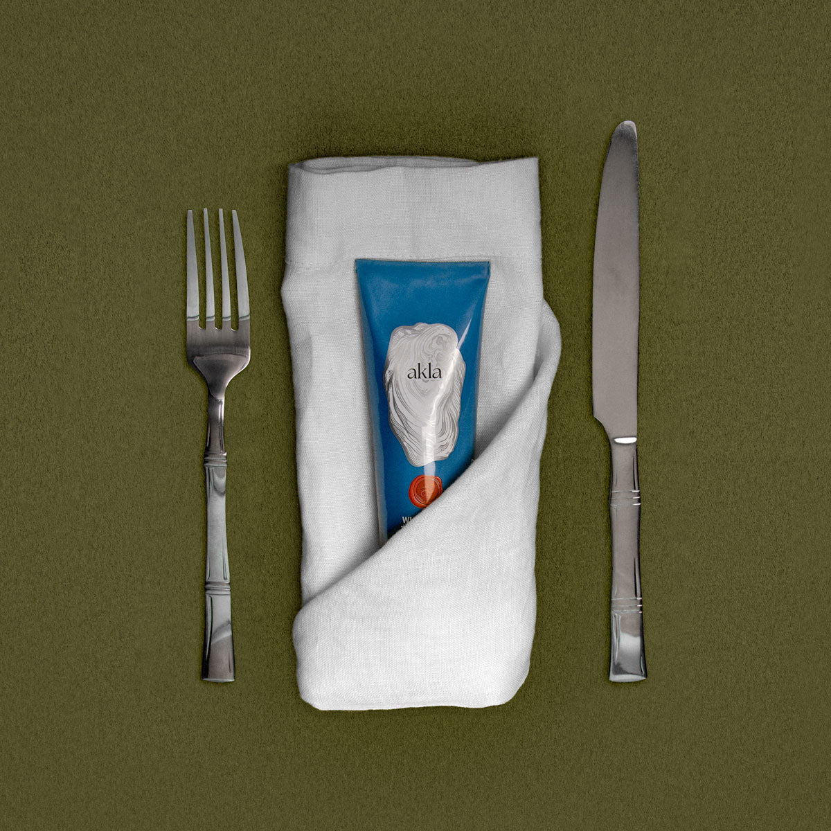 Akla toothpaste wrapped in linen napkin on dining table setting – morning ritual.