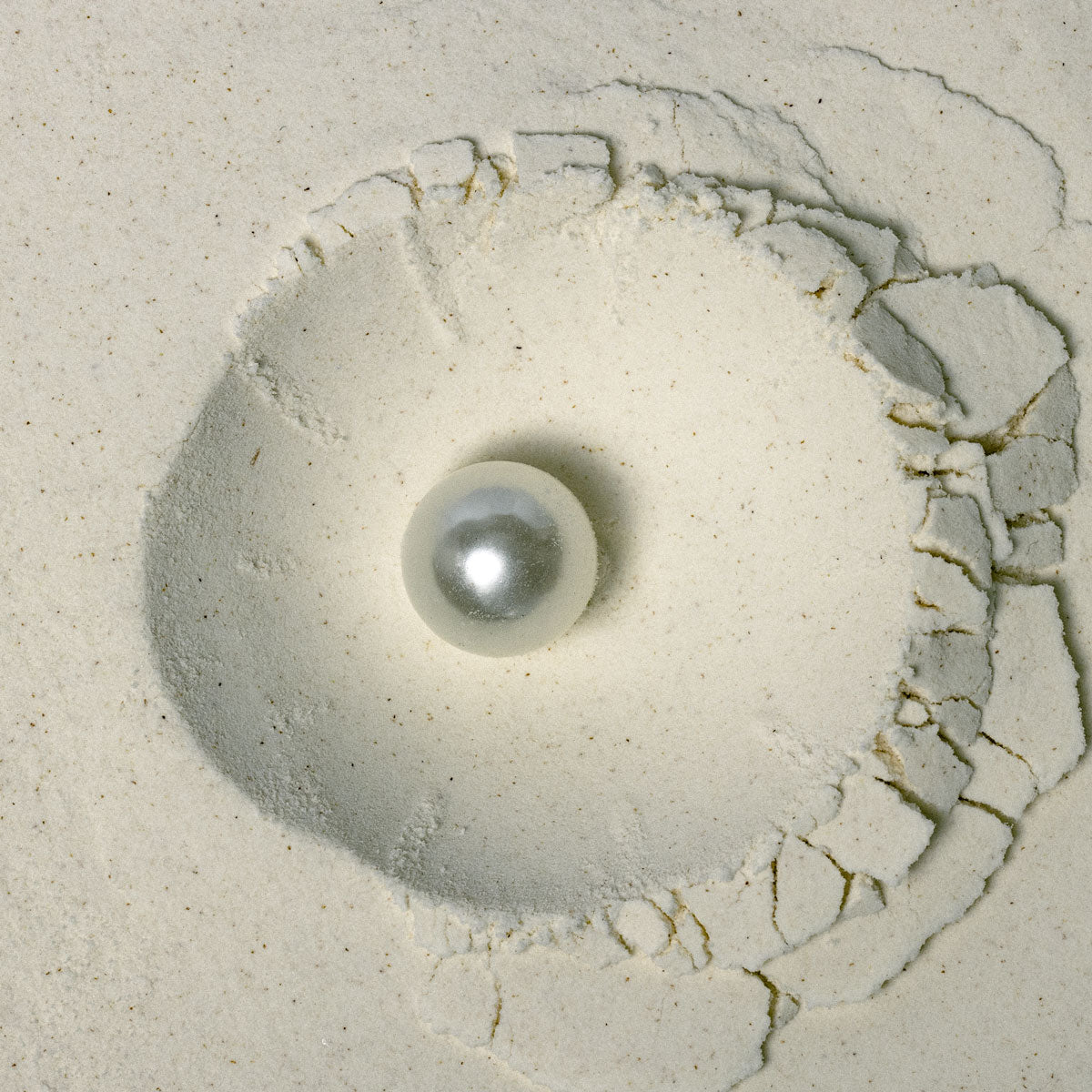 Close-up of pearl sitting in fine white powder – representing Akla’s oral care with pearl powder signature toohpaste ingredient.
